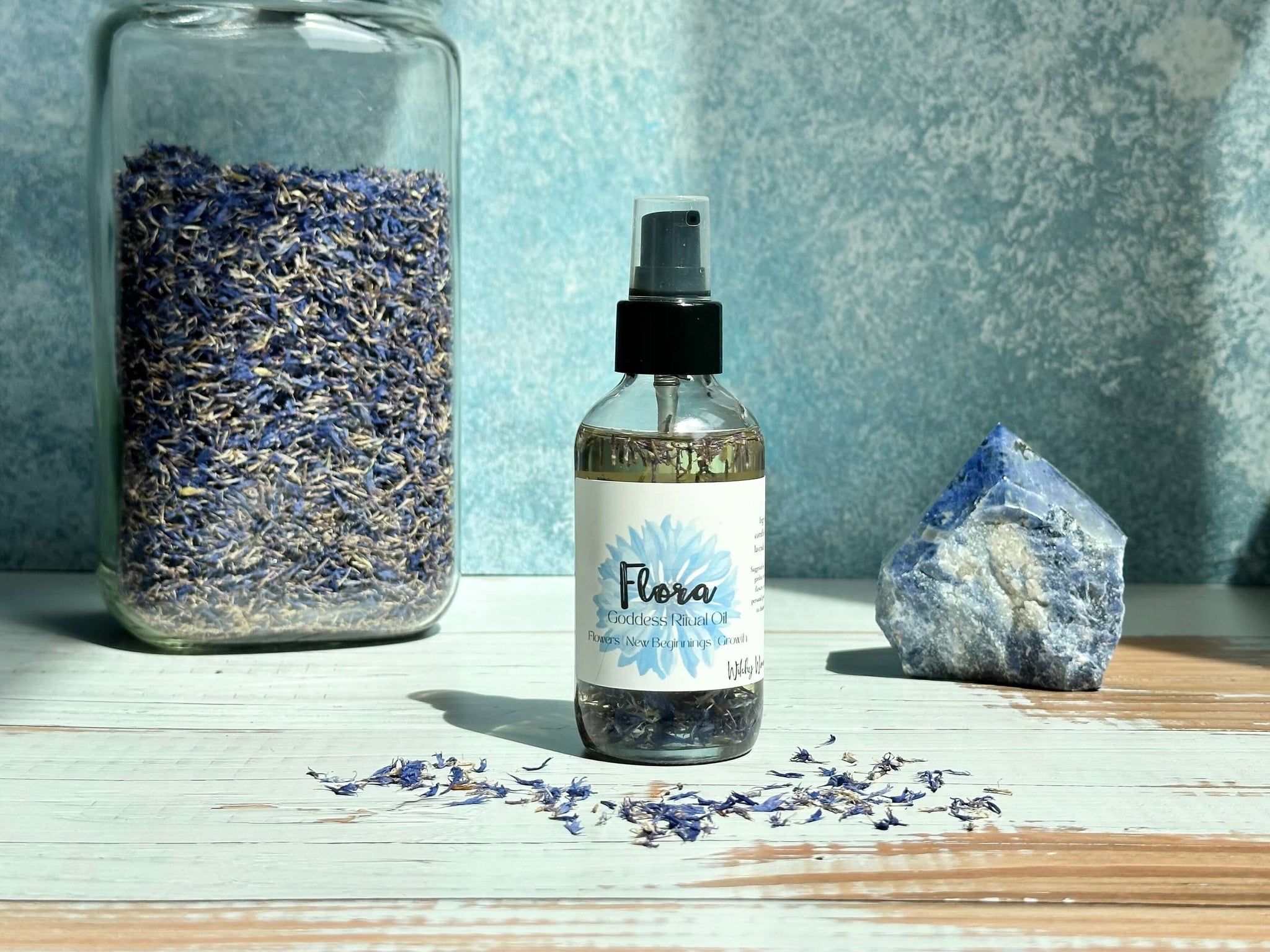 Bottle of Flora product with dried flowers and a crystal on a wooden surface