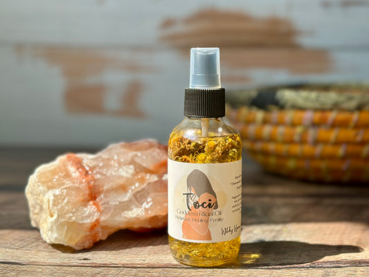 Bottle of Toci Goddess Ritual oil with a label featuring a woman's silhouette on a wooden surface with a rock and woven basket in the background.