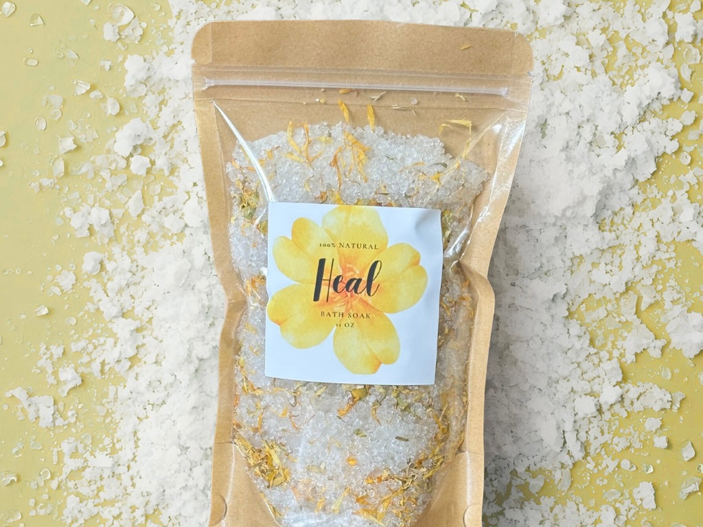Heal Bath Soak package surrounded by bath salts, promoting relaxation and self-care.