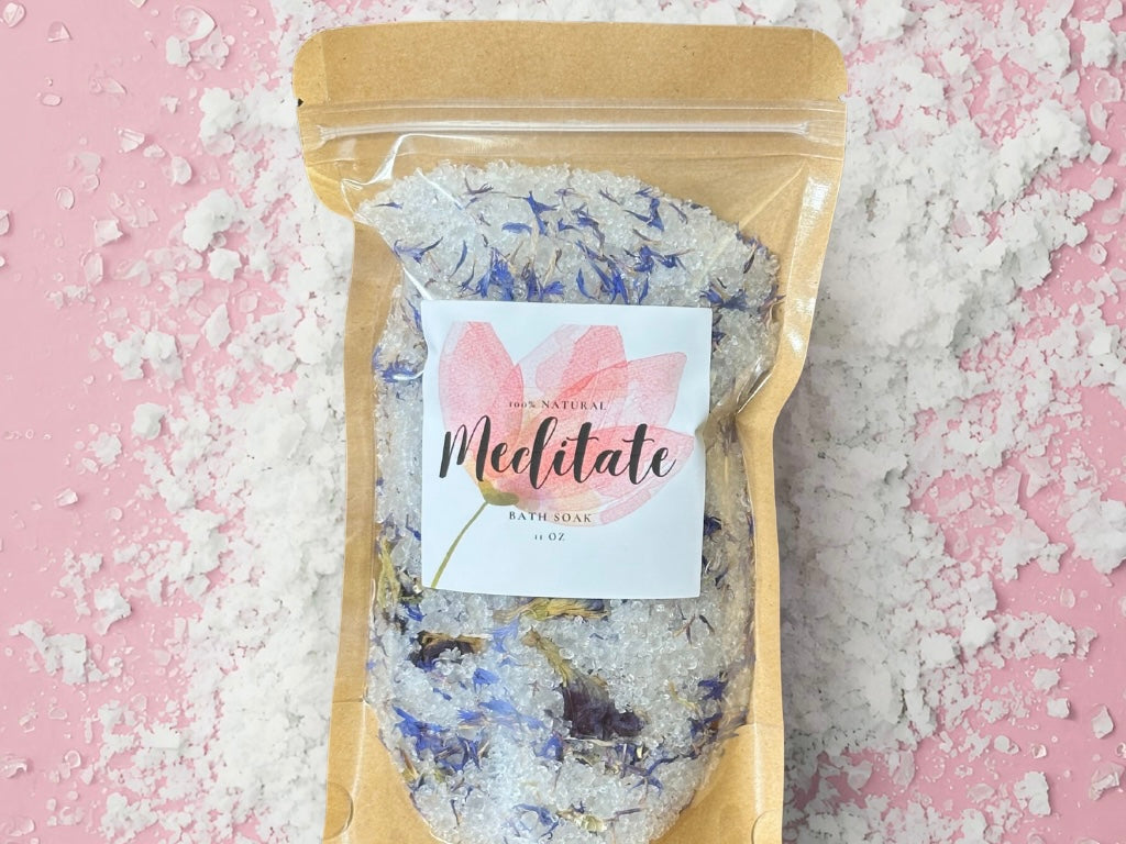 Meditate Bath Soak, a ritual bath soak with natural ingredients and beautiful packaging on a pink background.