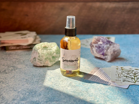 Saraswati Goddess Ritual Oil bottle on a table with crystals and artifacts, representing knowledge and creativity.