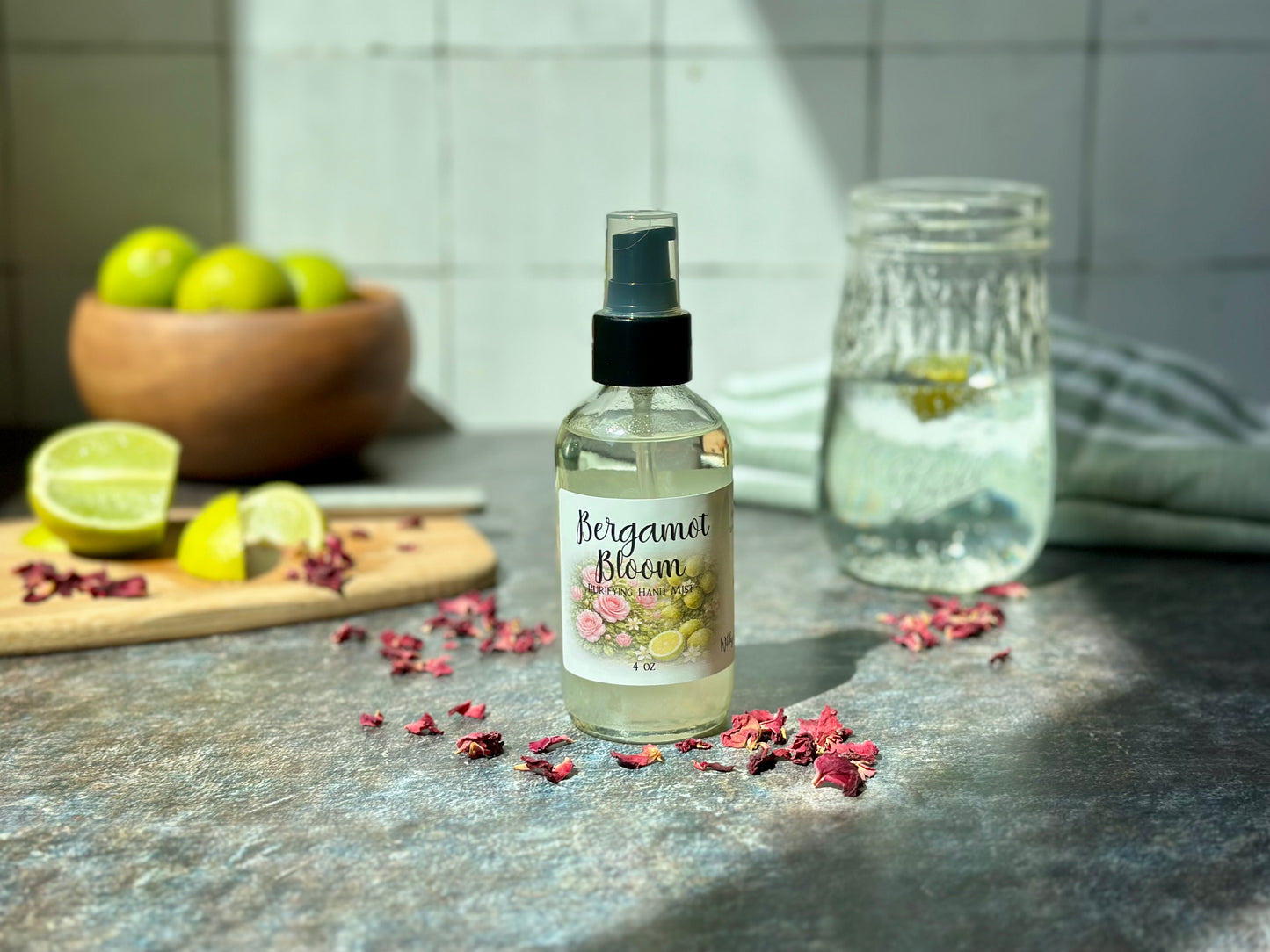 Bergamot Bloom Purifying Hand Mist bottle on a kitchen counter with bergamot and rose petals.