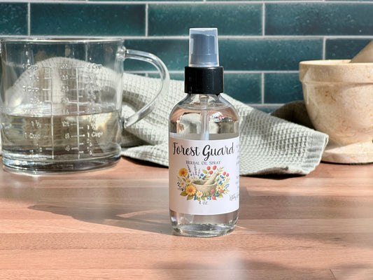 Bottle of 'Forest Guard' spray on a wooden surface with a measuring cup and towel in the background.