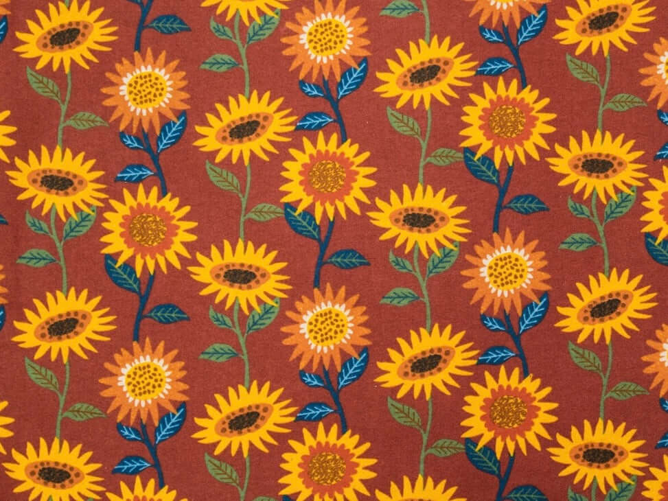 Rice heating pad made with soft cotton flannel with sunflowers printed all over it - orange background