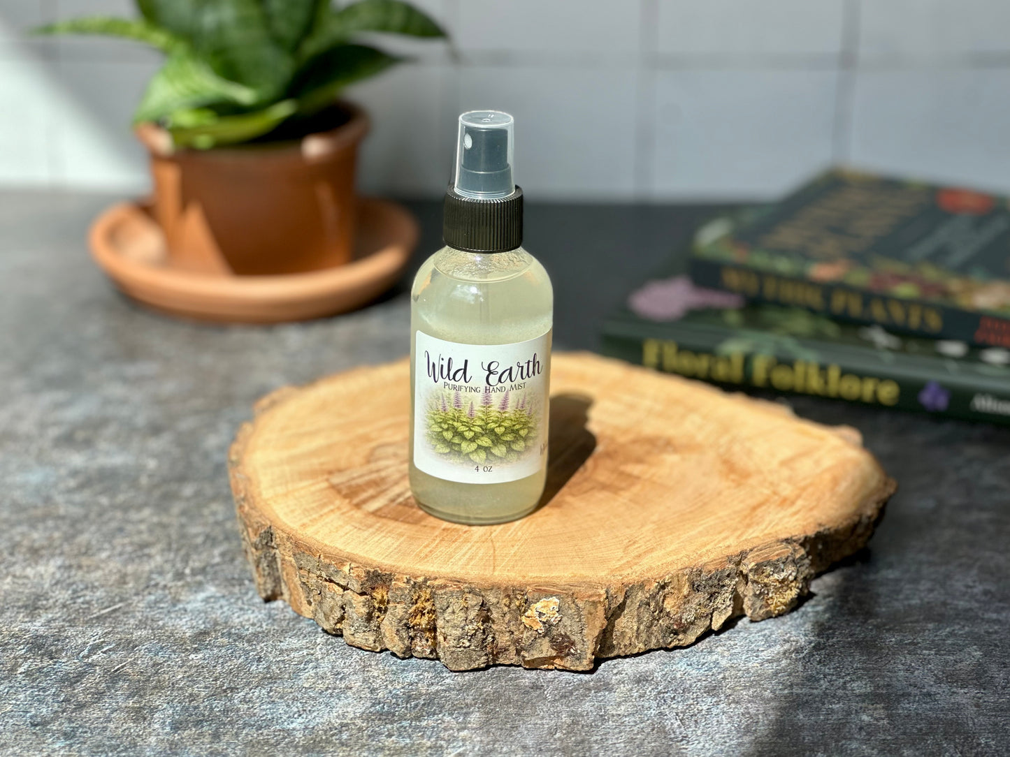 Bottle of Wild Earth Purifying Hand Mist displayed on a wooden surface with a background of plants and books.
