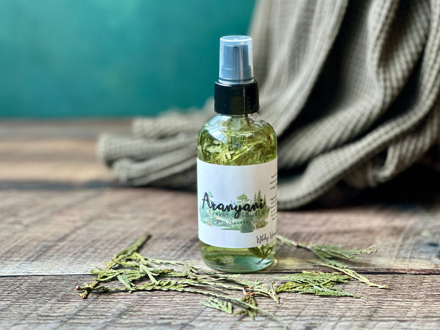 Bottle of Aranyani Goddess Ritual oil spray on a wooden surface with a green background