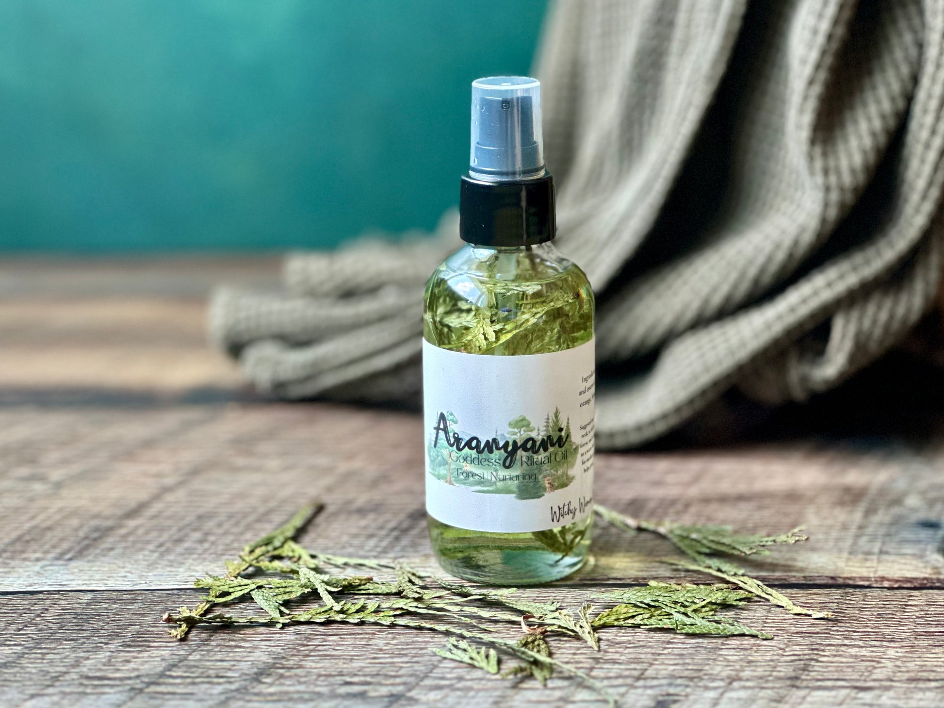 Bottle of Aranyani Goddess Ritual oil spray on a wooden surface with a green background