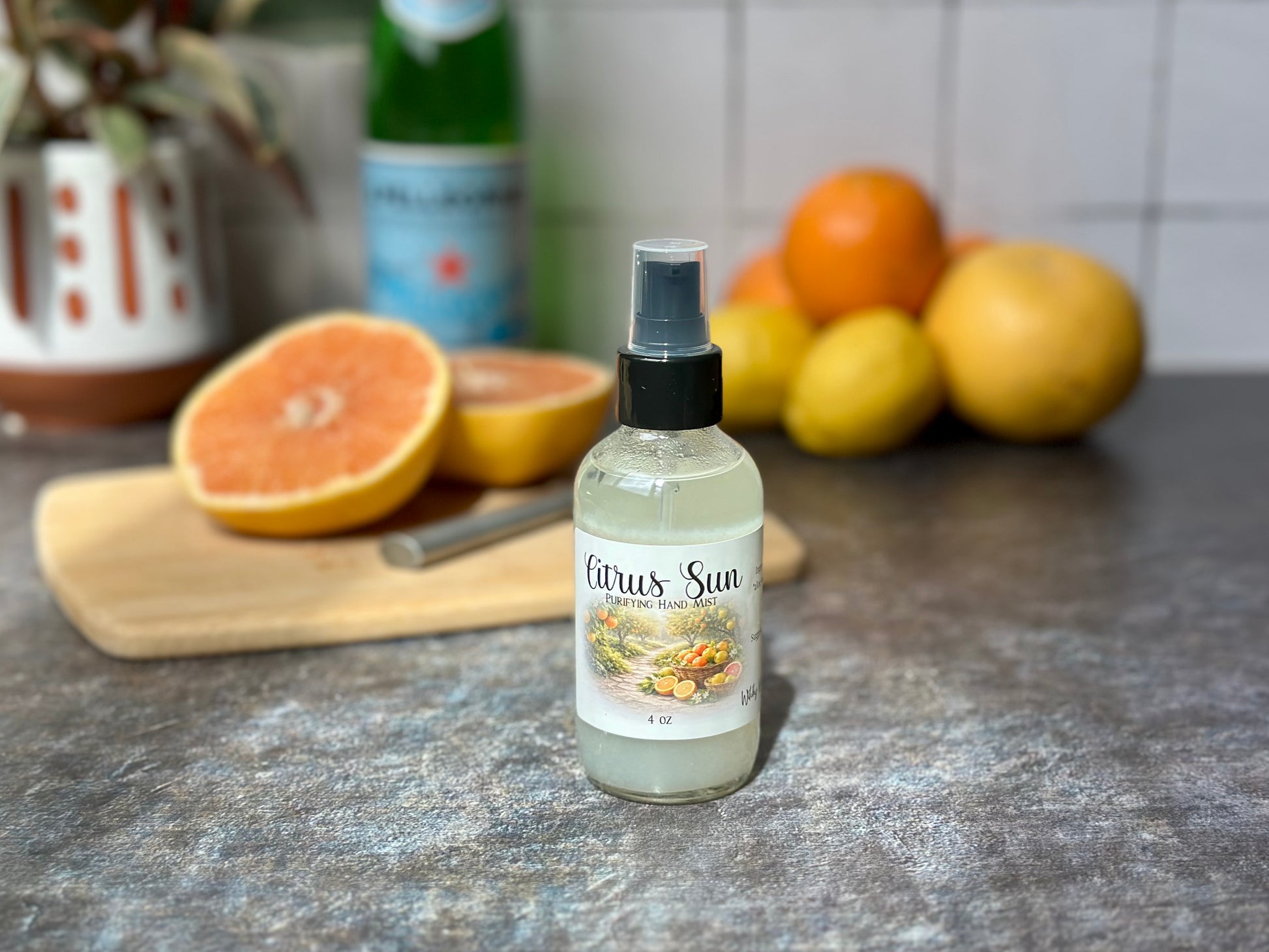 Citrus Sun Purifying Hand Mist bottle on a table with fresh citrus fruits in the background.