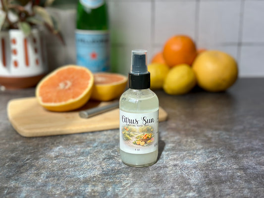 Citrus Sun Purifying Hand Mist bottle on a table with fresh citrus fruits in the background.