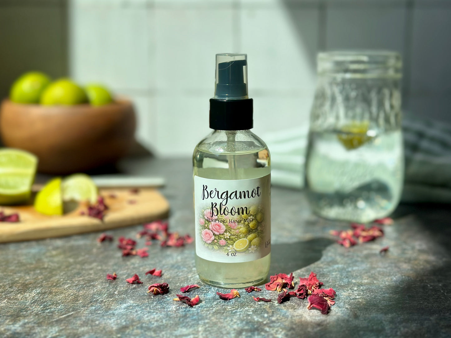 Bergamot Bloom Purifying Hand Mist bottle on a kitchen counter with bergamot and rose petals.