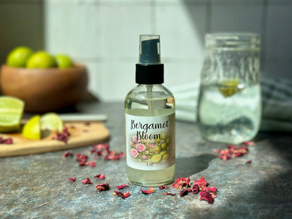 Bergamot Bloom Purifying Hand Mist bottle on a kitchen counter with bergamot and rose petals.