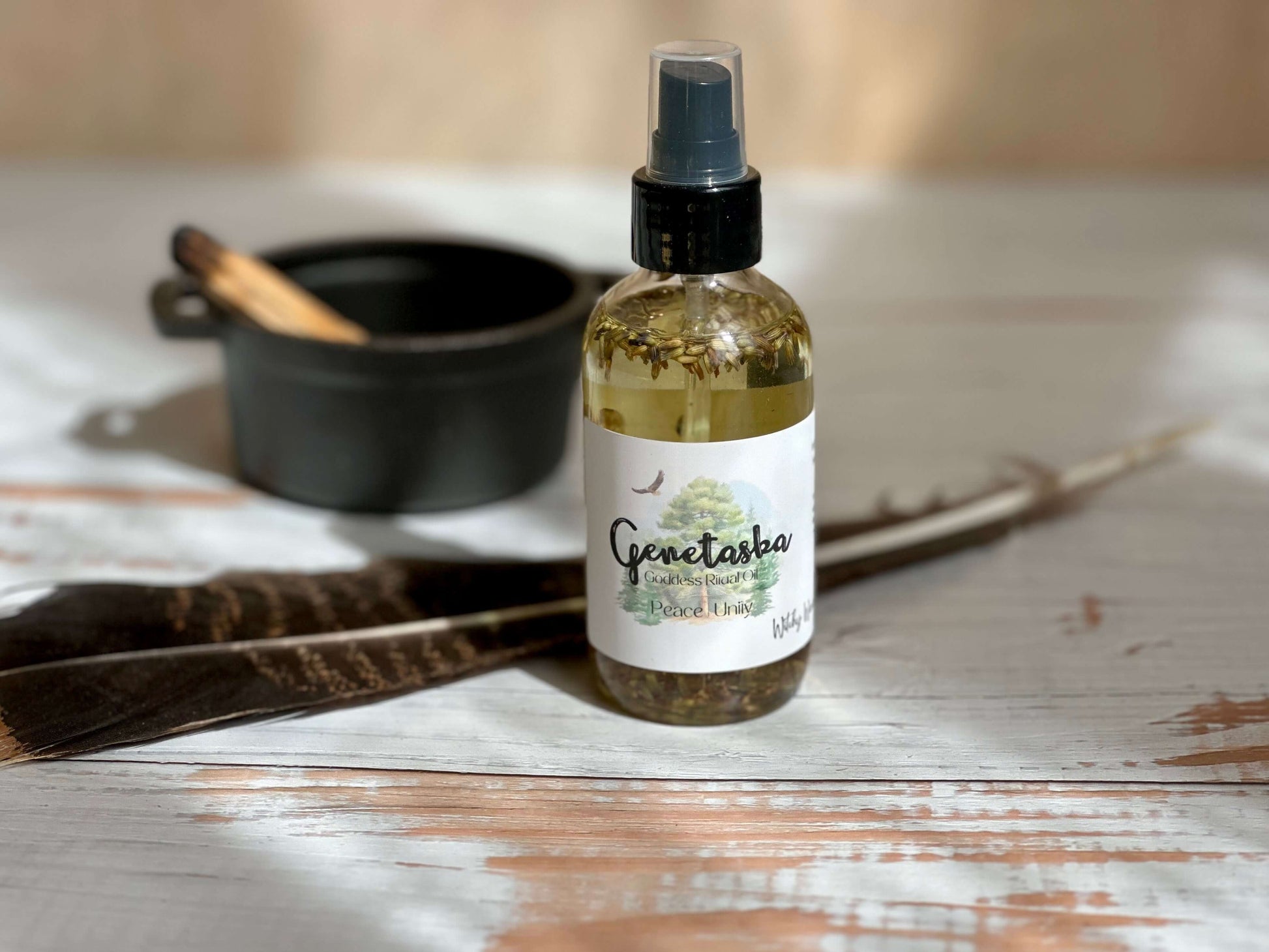 Genetaska Goddess Ritual Oil bottle with feathers and bowl in serene setting, promoting tranquility and inner peace.