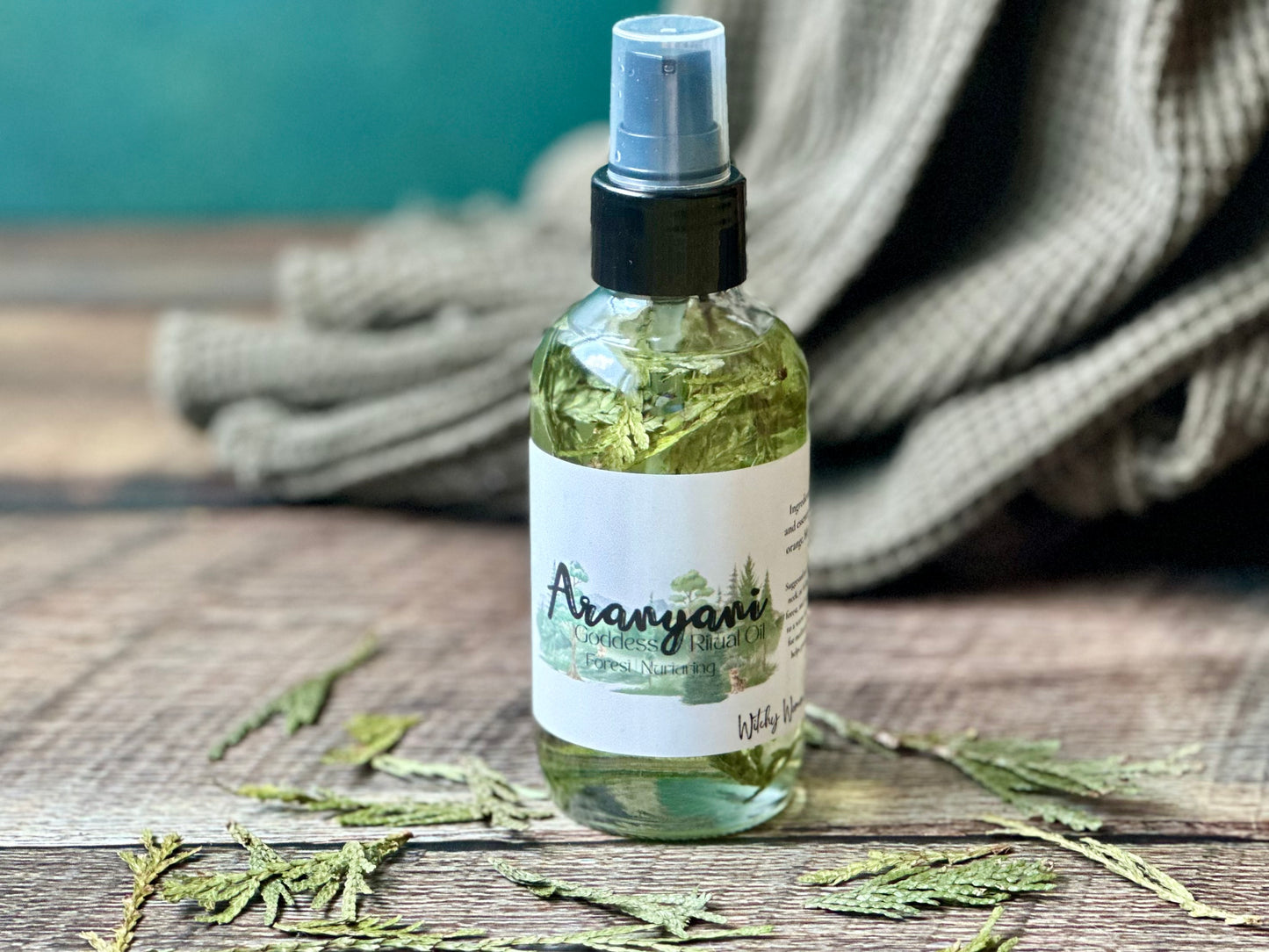 Aranyani Goddess Ritual Oil in a spray bottle surrounded by leaves on a wooden surface.