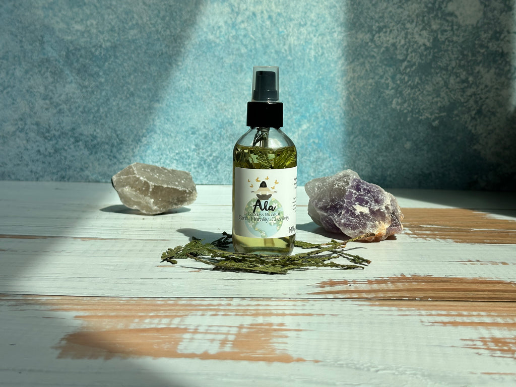 Spray bottle labeled 'Ala' on a wooden surface with stones and green leaves.