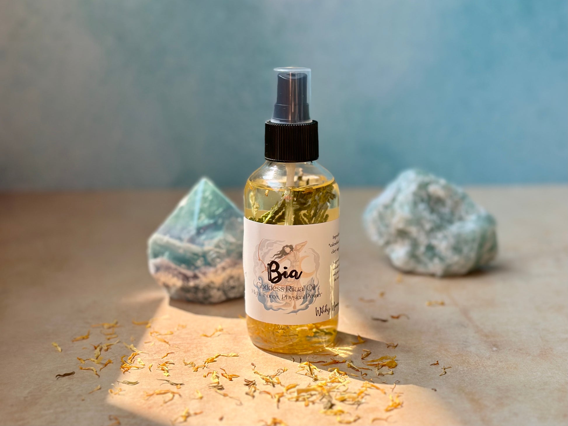 Bia Goddess Ritual Oil bottle surrounded by crystals and dried petals, embodying empowerment and confidence.
