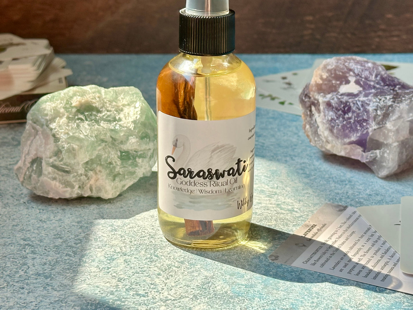 Bottle of Saraswati Goddess Ritual Oil with crystals and papers on a textured surface