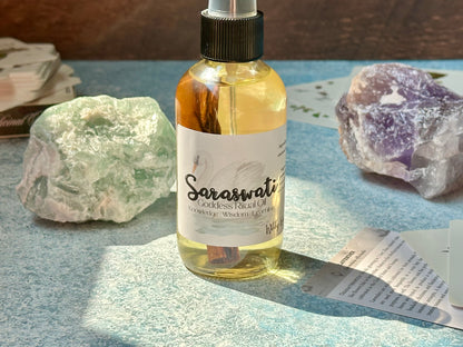 Bottle of Saraswati Goddess Ritual Oil with crystals and papers on a textured surface