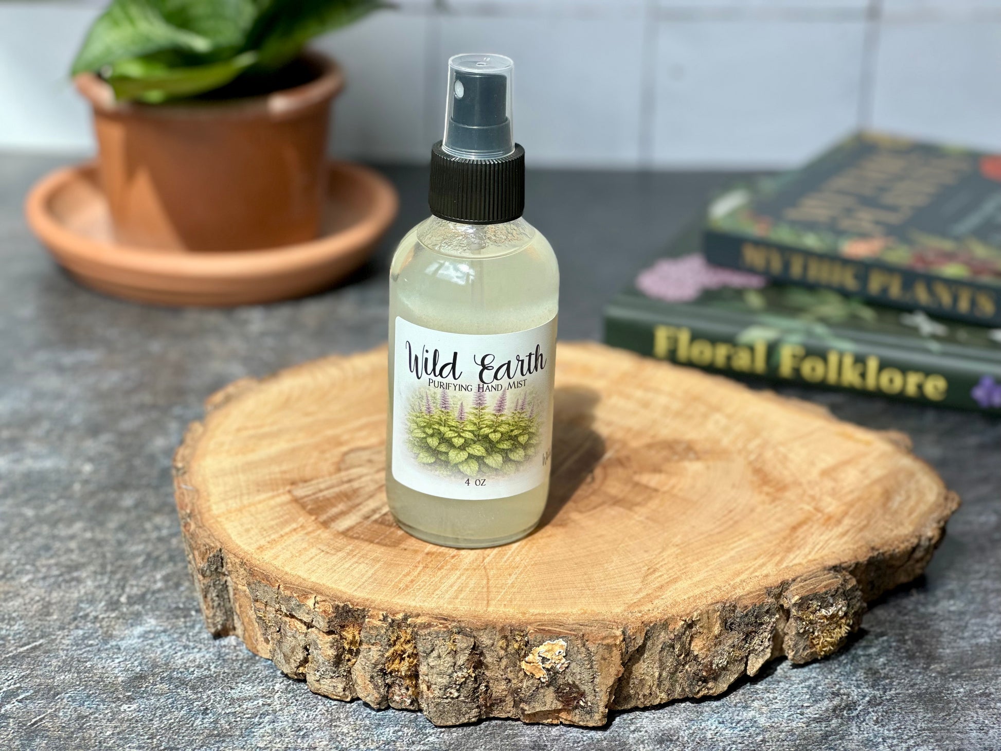 Bottle of Wild Earth Purifying Hand Mist displayed on a wooden surface with a background of plants and books.