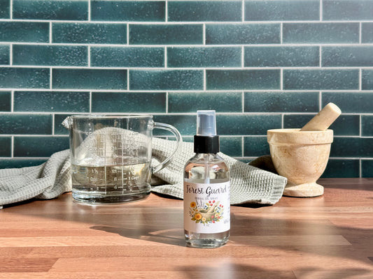 Bottle of 'Forest Guardian' on a wooden surface with a glass container and kitchen tools in the background.