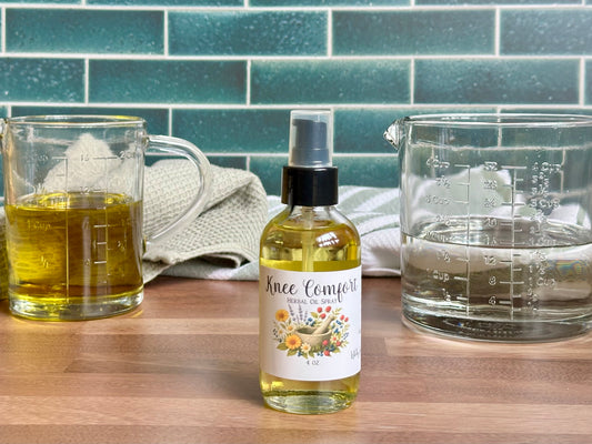 Bottle of 'Knee Comfort' spray on a wooden surface with glass measuring cups in the background.