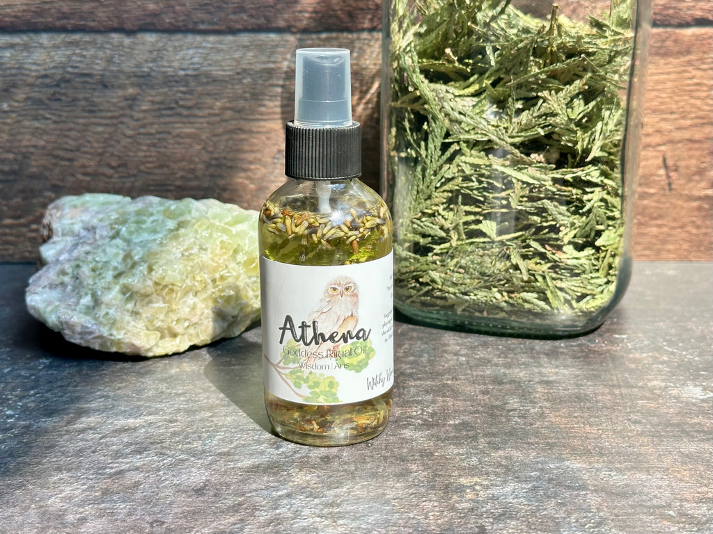 Bottle of Athena oil spray on a wooden surface with a jar of dried herbs and a rock.