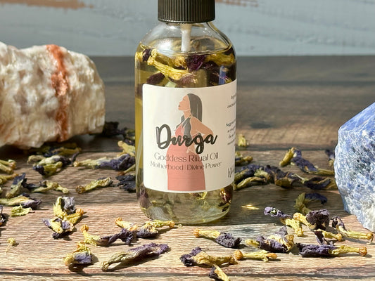 Durga Goddess Ritual Oil bottle surrounded by dried herbs and crystals, symbolizing inner strength and empowerment.