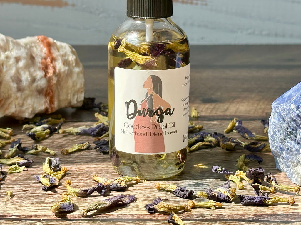 Bottle of Durga oil with a label on a wooden surface with dried flowers and stones.