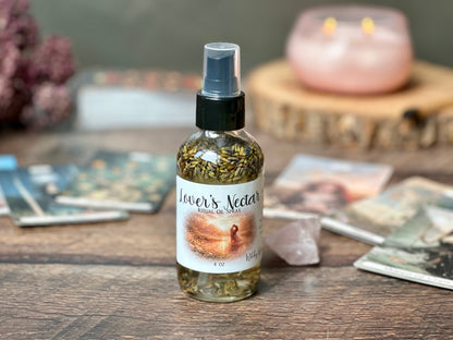 Lover's Nectar Ritual Oil Spray bottle displaying organic oils surrounded by candles and crystals.