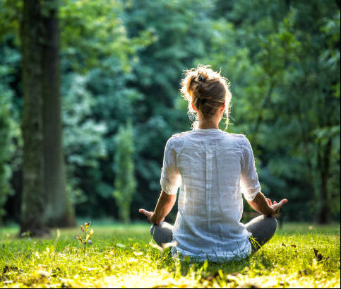 Person meditating in a park with greenery